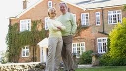 Baby boomer couple in front of home for sale
